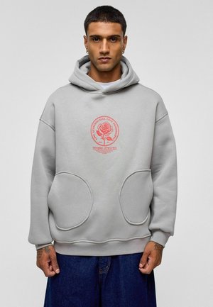 Grijze hoodie met grote voorkruiszakken, met een roze cirkelvormig grafisch ontwerp van een roos. Zachte stof met een comfortabele pasvorm en verstelbare capuchon.