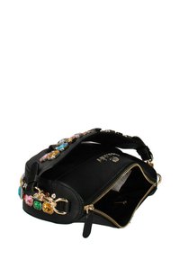 Sac à main en cuir noir avec ferrures dorées, doté d'une fermeture éclair et d'accents de pierres colorées sur la sangle. Intérieur visible, design ouvert.