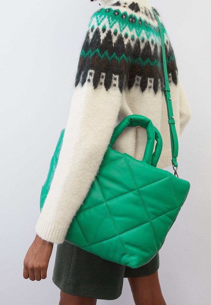 Groene gestikte tote bag gemaakt van soepel materiaal met een gestructureerd ontwerp, voorzien van twee handvatten en een afneembare schouderband.