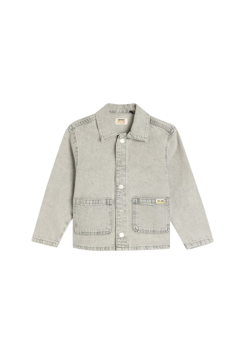Chaqueta de mezclilla gris claro con cuello de solapa, cierre central de botones, dos bolsillos frontales y una pequeña etiqueta amarilla en el bolsillo izquierdo.