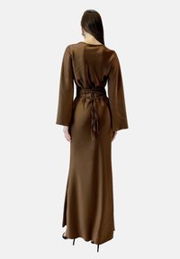 Robe longue en satin marron avec des manches longues et un détail de taille nouée, présentant une coupe droite et une texture lisse, vue de dos.