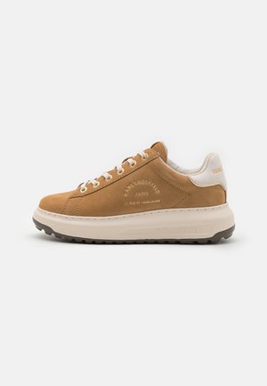 Tan low-top sneaker med hvide snørebånd og sål, præget "Karl Lagerfeld Paris" tekst og en polstret hvid hælkant.