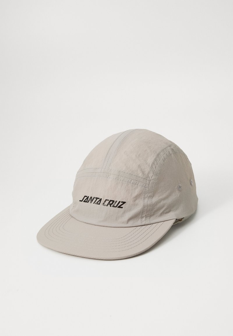 Boné bege feito de tecido leve. Apresenta uma aba plana, painéis costurados e o logotipo "SANTA CRUZ" na frente em preto. Possui dois orifícios de ventilação.