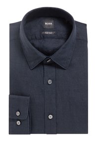 Složená tmavě modrá lněná košile s dlouhým rukávem, knoflíky, špičatým límcem a viditelnou značkovou etiketou uvnitř límce.