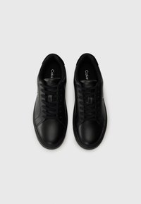 Zwarte leren sneakers met een gladde afwerking, ronde neus, vetersluiting en logo op de zijkant. Rubberen zool met een minimaal profiel.
