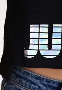 Black fabric with a reflective, silver segmented grid pattern partially visible above blue denim jeans.