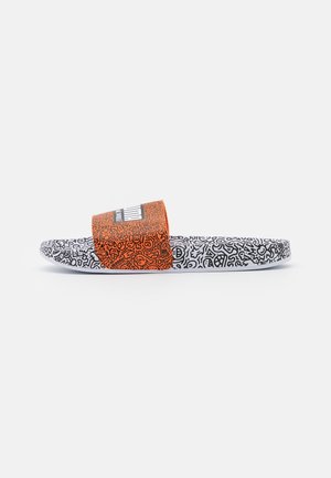 Slip sandal med hvid sål og sorte tegne-mønstre, med en orange rem med lignende sorte tegninger og en hvid brandlogo.