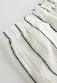 Lekko bawełniane spodenki z elastycznym pasem, ozdobione poziomymi paskami w kolorze granatowym i beżowym na kremowym tle.