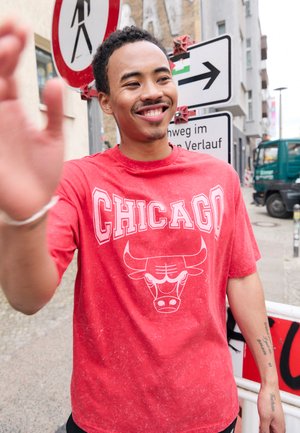 Maglietta di cotone rossa con la scritta "CHICAGO" in bianco e una grafica di un toro, maniche corte e una trama leggermente sbiadita.