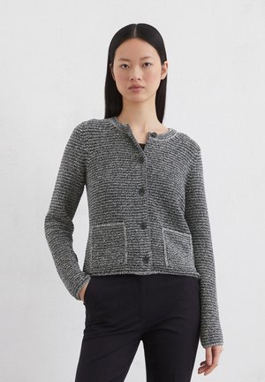 Schwarzer und weißer strukturierter Cardigan mit rundem Kragen, Knopfverschluss und zwei vorderen Taschen. Verfügt über lange Ärmel und eine taillierte Passform.