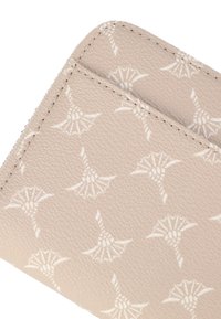 Portafoglio beige con una finitura testurizzata, caratterizzato da un motivo floreale bianco ripetuto e cuciture a contrasto lungo i bordi. Due fessure per schede visibili.