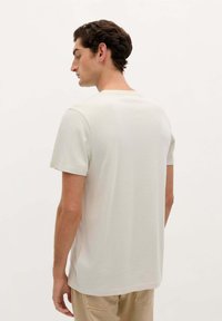 Hellgraues T-Shirt mit kurzen Ärmeln und Rundhalsausschnitt in lockerer Passform, aus weichem Stoff, von hinten gezeigt.
