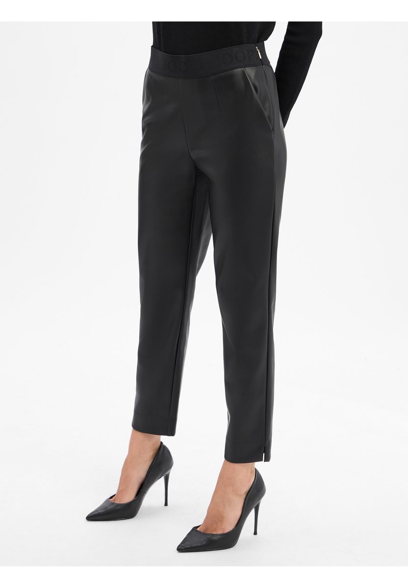 Pantaloni in ecopelle nera con una cintura alta, pieghe frontali e tasche laterali. Abbinati a tacchi a spillo neri per un look elegante.