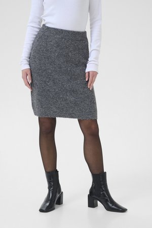 Jupe crayon en tricot gris avec une finition texturée, dotée d'une taille côtelée. Associée à des bottines noires et des collants fins.