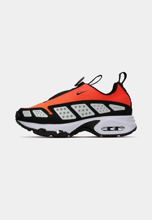 Sneaker nera e arancione con parte superiore in rete, prominente intersuola bianca e suola in gomma con dettagli testurizzati e un tassello per il sollevamento.