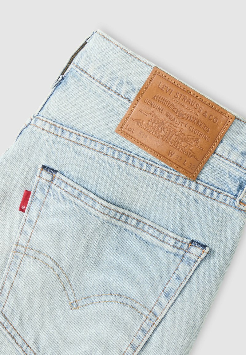 Light blue Levi's jeans folded to show back pocket, stitching, red tag, and brown leather Levi Strauss & Co. patch with size details.