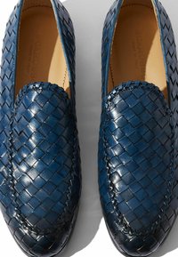 Mocasines de cuero azul trenzados con un acabado liso, que presentan una punta redondeada y costuras contrastantes a lo largo de los bordes.