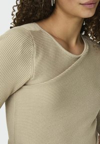 Top in maglia a coste beige con scollo rotondo e maniche corte, caratterizzato da una trama sottile e una vestibilità slim.