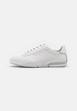 Weißer Leder-Sneaker mit niedrigem Schnitt, Schnürverschluss und grauen Akzenten an Sohle und Ferse, Seitenansicht auf weißem Hintergrund.