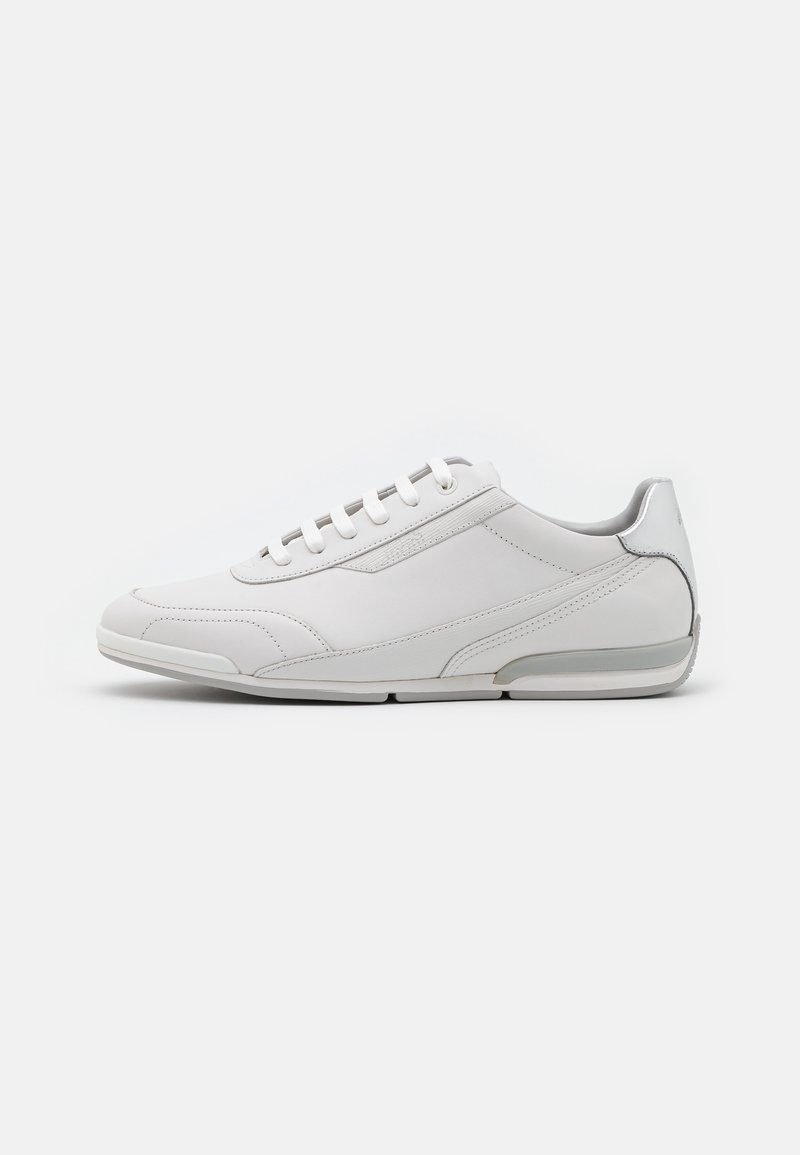 Baskets basses en cuir blanc avec fermeture à lacets et accents gris sur la semelle et le talon, vues de côté sur fond blanc.