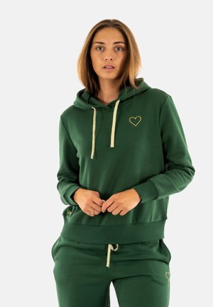 Green hoodie made of soft fabric, featuring a gold heart logo and light-colored drawstrings. It has a relaxed fit and ribbed cuffs.