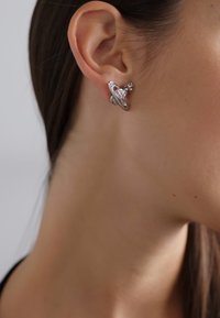 Pendientes de plata con un diseño espiral único, que presenta un pequeño acento en forma de estrella. Textura suave con un acabado pulido.