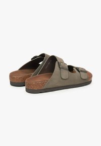 Grijze suède slippers met twee verstelbare gespen, kurken tussenzool en een bruine buitenzool. Het open ontwerp vergroot de ademend vermogen en het comfort.