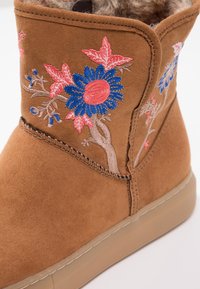 Ruske suede ankle bootit, joissa on sininen ja vaaleanpunainen kukkakirjonta, pehmeä sisävuori ja beige kumipohja.