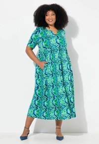 Maxikleid in grünen und blauen Mustern, kurze Ärmel, V-Ausschnitt, geraffte Taille mit Taschen, fließender Stoff, knöchellang.