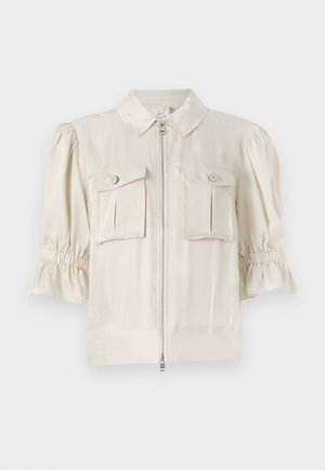 Kermanvärinen lyhyttaittuinen paita, jossa on kaulus, vetoketju edessä, kaksi nappietä elin ja rypytetty yksityiskohta hihansuiden reunassa. Tasainen kangas.