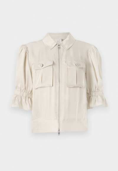 Krémfargede kortermede bluse med krave, frontlynt, to knaplukket lommer og rynkede detaljer ved ærmekanterne. Glat stof.