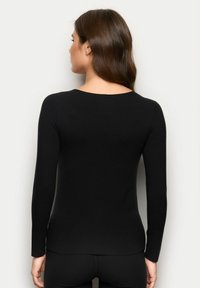 Schwarzes Langarmoberteil mit rundem Ausschnitt, figurbetontem Schnitt und glatter Textur. Der Rücken hat einen leicht kurvigen Saum für einen modernen Look.