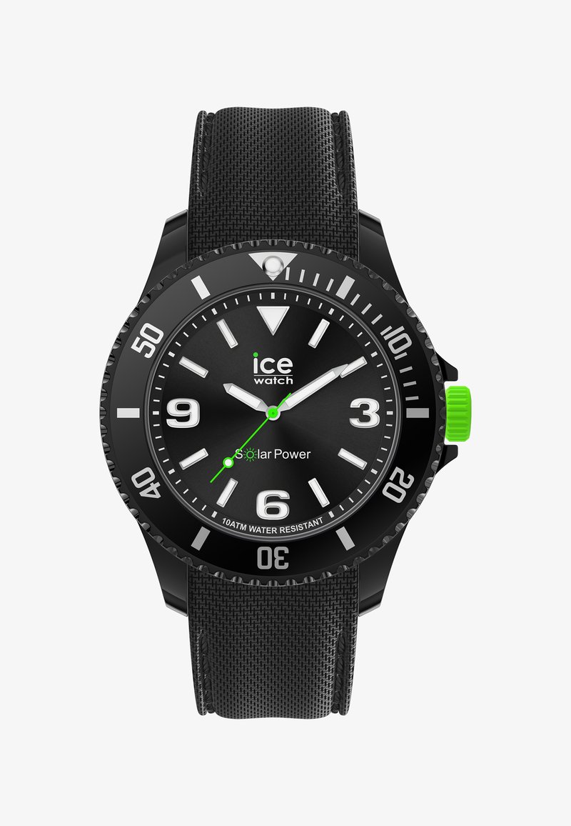 Svart solcellsdriven klocka med en texturerad gummirem, rund svart urtavla, vita timmarkörer, tre visare och en grön accent på kronan.