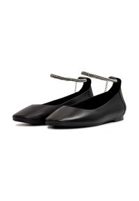 Zapatos planos negros con diseño de punta, hechos de cuero suave. Presentan una cadena decorativa alrededor del tobillo. Suela de bajo perfil.