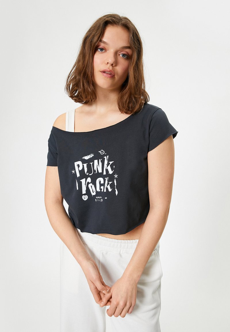 T-shirt nera corta con una vestibilità ampia e design scollo asimmetrico, caratterizzata da una stampa grafica bianca "PUNK" e maniche corte. Tessuto morbido.