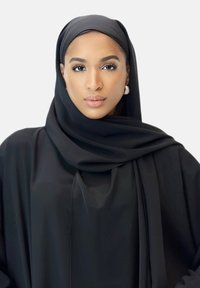 Schwarzer Hijab und Abaya, glatte Textur, ausgestelltes Design, elegante Silhouette, die die Gesichtszüge und großen Ohrringe betont.