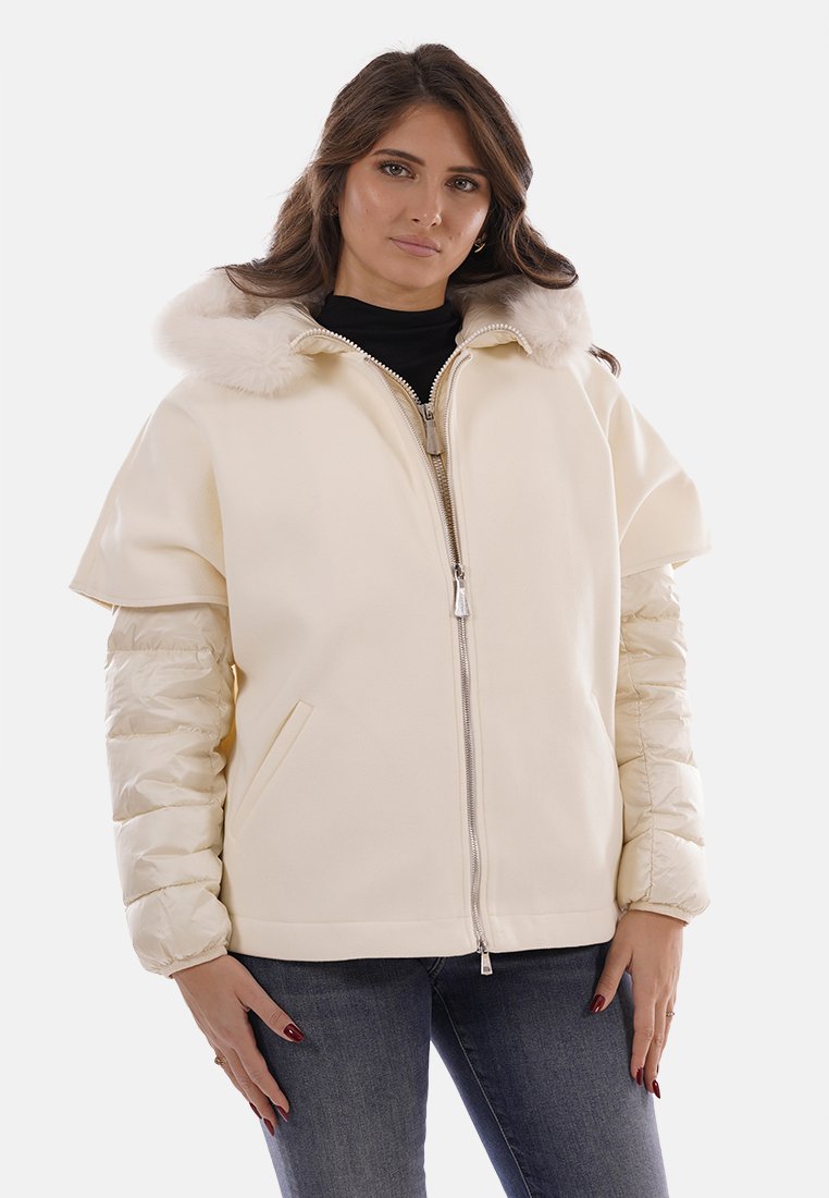 Giacca color crema con cappuccio soffice, dotata di corpo aderente e maniche gonfie. Realizzata in tessuto morbido con una texture liscia e cerniera argentata.