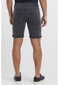 Shorts di denim grigio scuro con un effetto leggermente slavato, orlo risvoltato e due tasche posteriori, abbinati a sneakers nere.