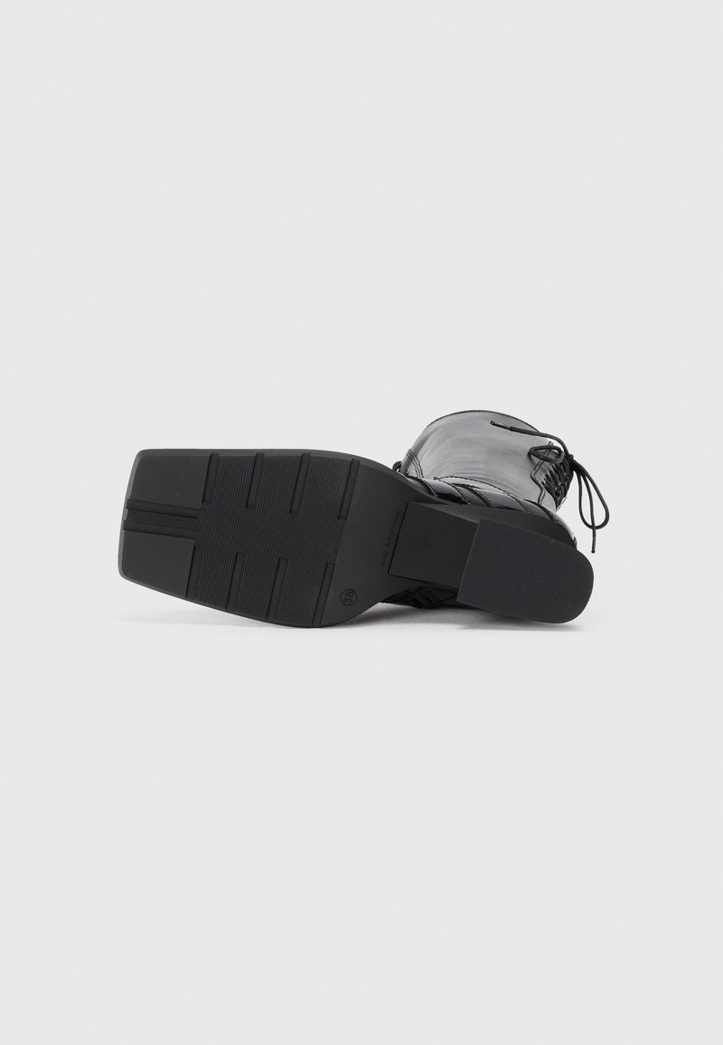 Schwarze Knöchelstiefel mit Obermaterial aus strukturiertem Leder, runder Zehenform und einer stabilen Gummisohle mit horizontalen Rillen für besseren Halt.