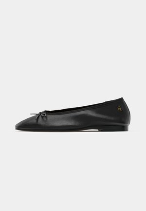 Black leather ballet flat with a pointed toe, small bow accent, and subtle logo detail on the heel, featuring a low profile and smooth texture.
