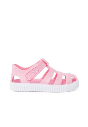 Pink rubber sandal featuring a strappy design, white sole, adjustable buckle, and textured footbed for grip.