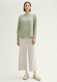 Lichtgroene sweater met een gestructureerde afwerking en een bootneck, in combinatie met losse, crèmekleurige wijde broek en beige plateauschoenen.