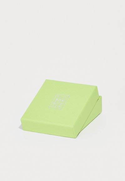 Caja de papel verde con una superficie texturizada, que presenta un logo plateado en la parte frontal. Diseño inclinado con un cierre de solapa.