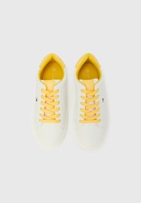 Sneakers bianche con lacci, talloni e rivestimento interno gialli, misura 36, disposti fianco a fianco su uno sfondo bianco.