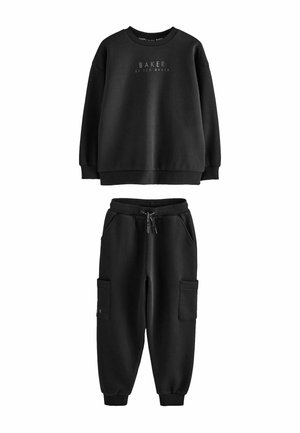 Must üle suur pusa, millel on kiri "Baker by Ted Baker", ning sobivad mustad jogger-püksid, millel on nöörvöökoht ja küljetaskud.