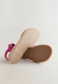 Fuchsia espadrillessandaler med en texturerad fotbädd, vävd jute-mellansula och justerbart ankelsnöre med ett gyllene spänne. Platt gummisula.