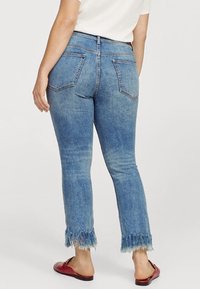 Jeans in denim di colore azzurro chiaro con orlo sfilacciato. Presentano un'alta vita, due tasche posteriori e un design aderente.