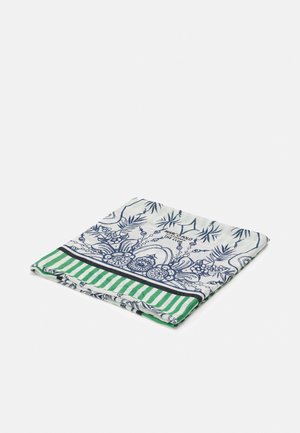 Složený bílý šátek s modrými květinovými a listovými vzory a zeleno-bíle pruhovaným lemem na jednobarevném pozadí.