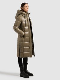 Abrigo largo acolchado en verde oliva con acabado brillante, con capucha, bolsillos con cremallera y un patrón de cuadros. Combinado con botas negras.