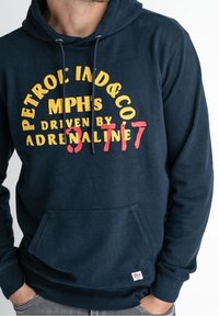 Granatowa bluza z kapturem wykonana z bawełny, z przednią kieszenią, kapturem ze sznurkiem i wyraźną grafiką z żółto-czerwonym napisem.